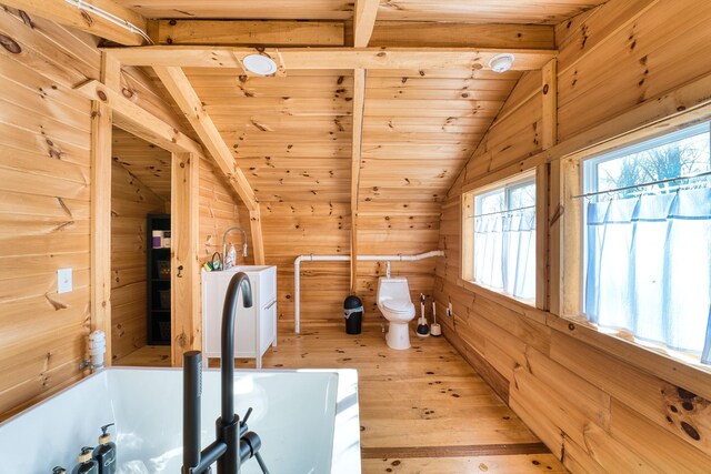 bathroom with wooden ceiling, a bath, wooden walls, vaulted ceiling with beams, and toilet