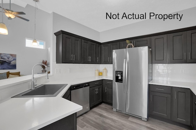 kitchen with sink, light hardwood / wood-style flooring, tasteful backsplash, decorative light fixtures, and stainless steel appliances