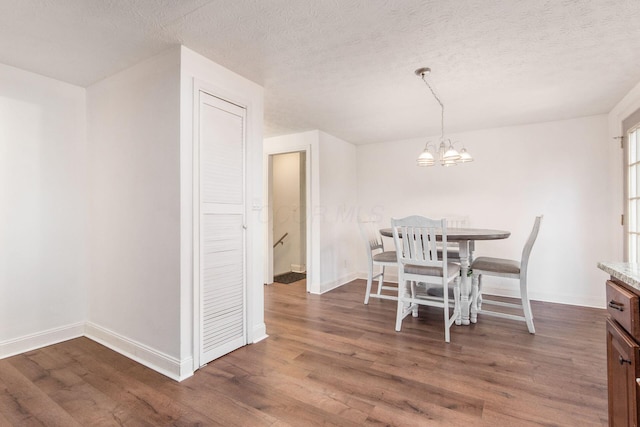 dining room featuring a textured ceiling, dark hardwood / wood-style floors, and an inviting chandelier