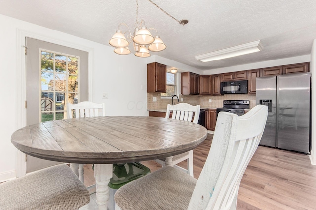 dining space featuring light hardwood / wood-style floors, a textured ceiling, and a chandelier