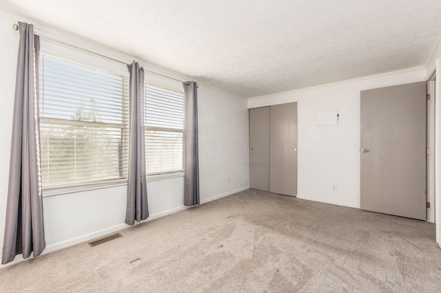 carpeted empty room featuring a textured ceiling and ornamental molding