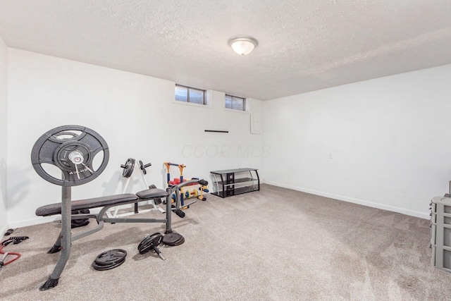 exercise area with light carpet and a textured ceiling