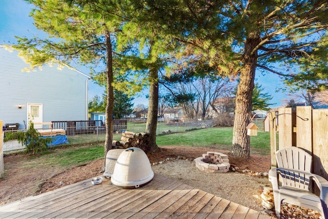 wooden terrace with a fire pit and a yard