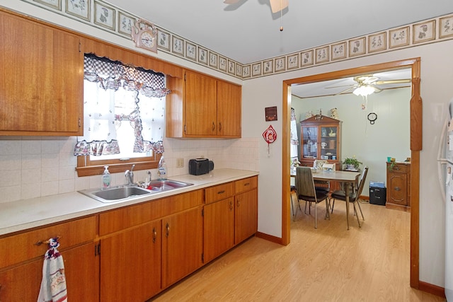 kitchen with tasteful backsplash, sink, and light wood-type flooring