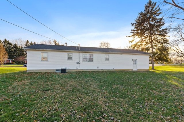 back of house with central air condition unit and a yard