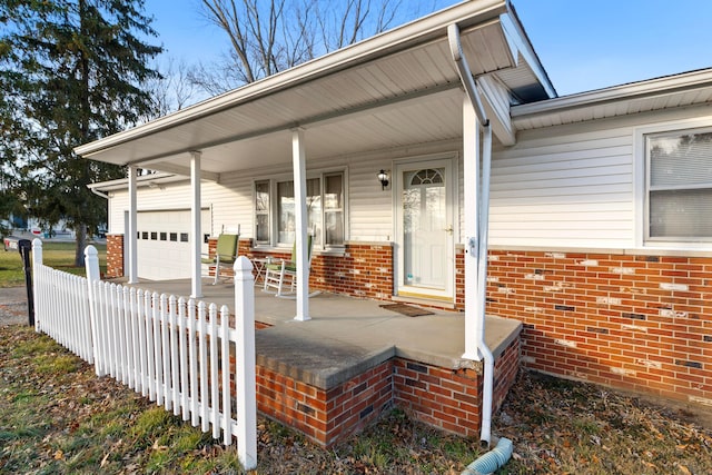 view of exterior entry featuring a porch and a garage