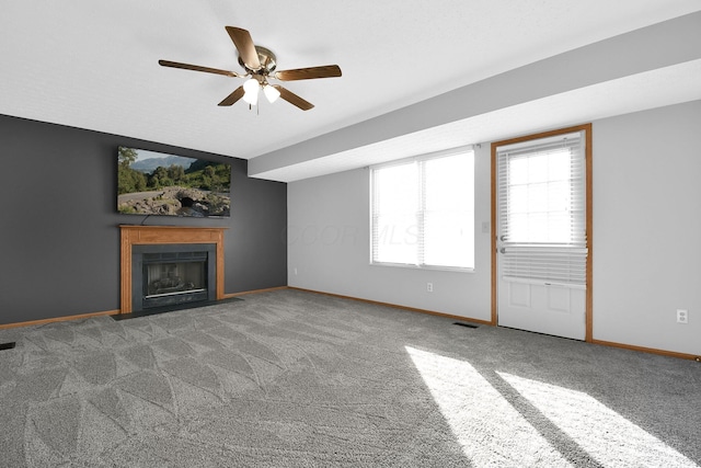 unfurnished living room with ceiling fan and dark colored carpet