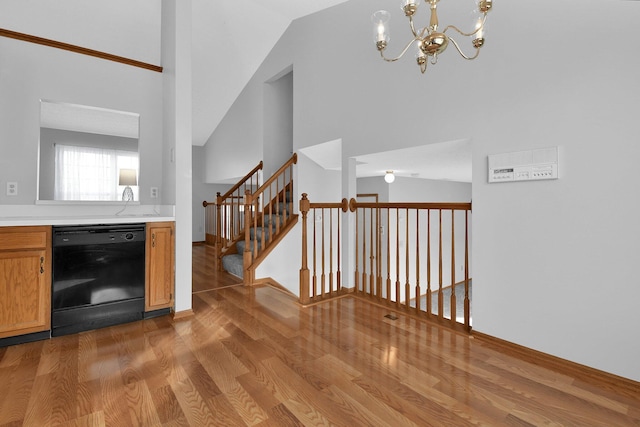 bar featuring dishwasher, light hardwood / wood-style floors, vaulted ceiling, and an inviting chandelier