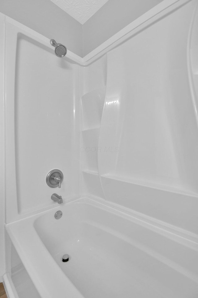 bathroom featuring shower / bathing tub combination and a textured ceiling