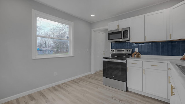 kitchen with tasteful backsplash, white cabinetry, stainless steel appliances, and light wood-type flooring