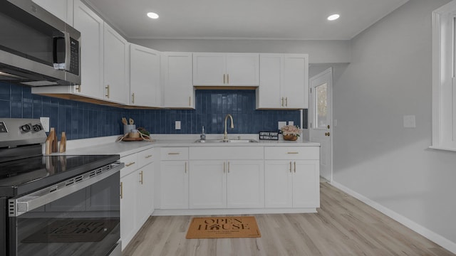 kitchen with appliances with stainless steel finishes, tasteful backsplash, sink, white cabinets, and light hardwood / wood-style floors