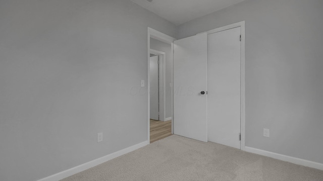 unfurnished bedroom featuring light carpet and a closet