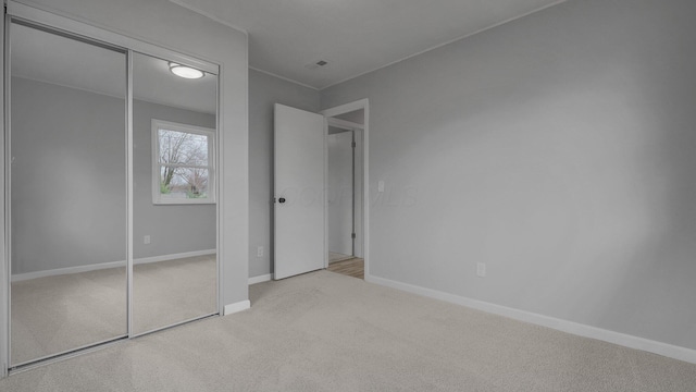 unfurnished bedroom featuring light colored carpet and a closet