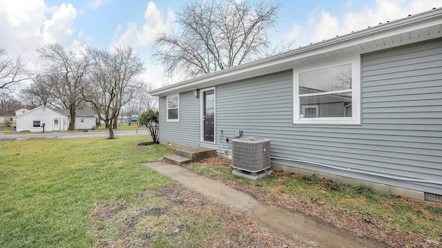 view of side of home with central AC and a yard