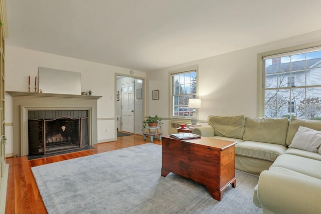 living room featuring wood-type flooring and a brick fireplace