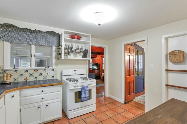 kitchen with tile countertops, white cabinetry, light tile patterned flooring, and white gas range oven