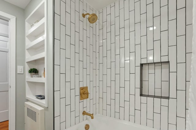 bathroom featuring radiator heating unit and tiled shower / bath