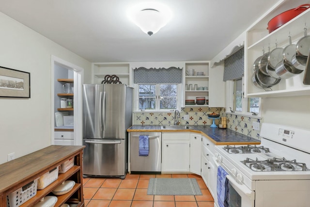 kitchen with white cabinets, a wealth of natural light, light tile patterned flooring, and appliances with stainless steel finishes