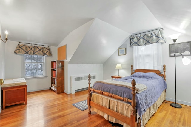 bedroom featuring radiator heating unit, light hardwood / wood-style floors, and lofted ceiling