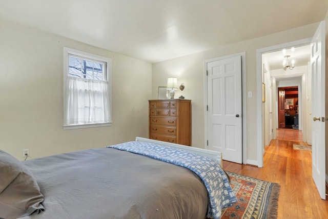 bedroom with light hardwood / wood-style floors and a chandelier