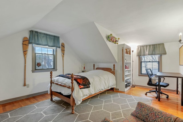 bedroom with multiple windows, hardwood / wood-style floors, and lofted ceiling