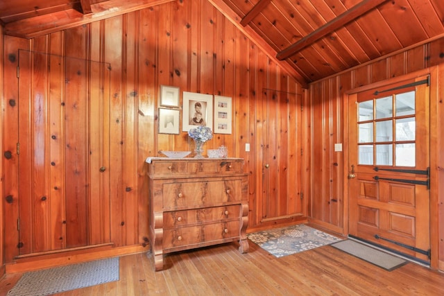 doorway to outside featuring wood walls, hardwood / wood-style floors, wooden ceiling, and lofted ceiling