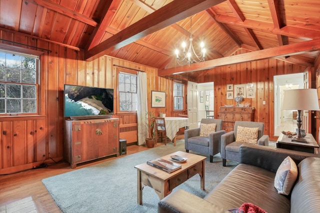 living room featuring light wood-type flooring, lofted ceiling with beams, an inviting chandelier, and wood walls