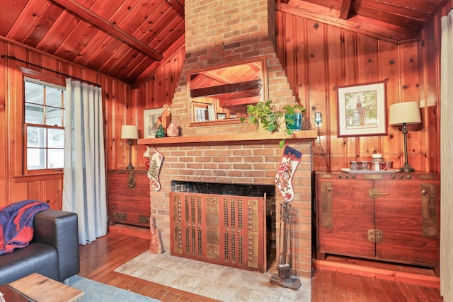 living room with wood walls, wood-type flooring, a fireplace, and vaulted ceiling