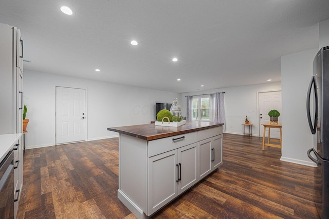 kitchen featuring butcher block countertops, stainless steel refrigerator, dark hardwood / wood-style flooring, and white cabinets