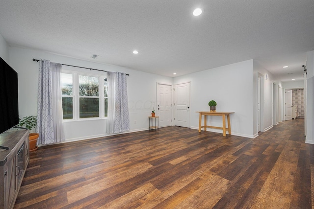 unfurnished living room featuring dark hardwood / wood-style flooring and a textured ceiling