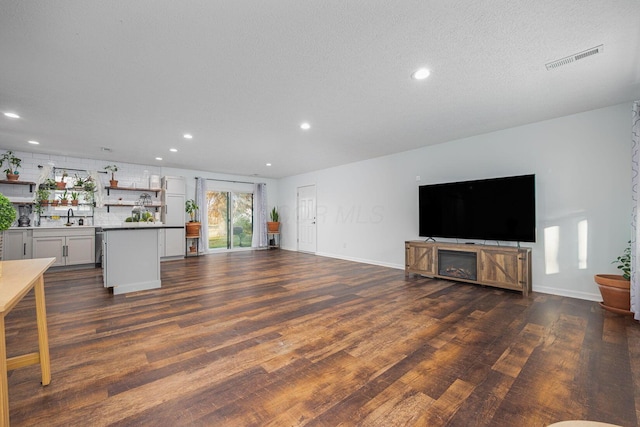 unfurnished living room with a textured ceiling, dark hardwood / wood-style floors, and sink