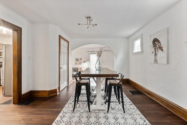 dining room with dark hardwood / wood-style flooring, ornamental molding, and an inviting chandelier