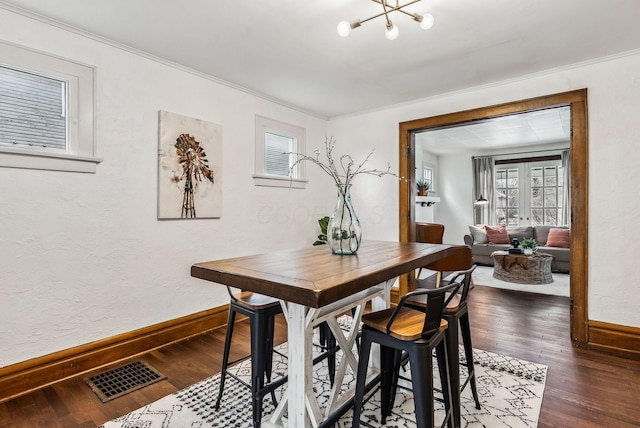 dining area with an inviting chandelier, crown molding, and dark wood-type flooring