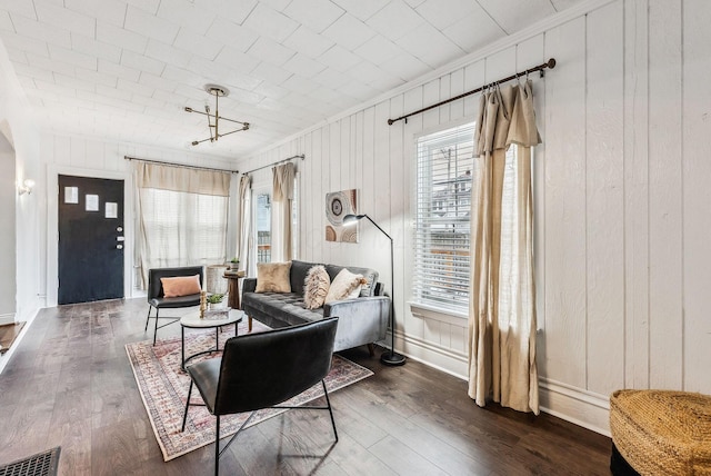 living room with dark hardwood / wood-style flooring and wood walls