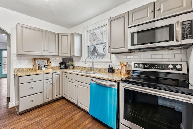 kitchen featuring sink, appliances with stainless steel finishes, gray cabinetry, light stone counters, and dark hardwood / wood-style flooring