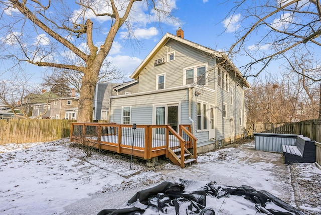 snow covered back of property with a wooden deck