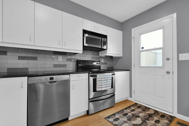 kitchen featuring appliances with stainless steel finishes, white cabinetry, backsplash, and light wood-type flooring