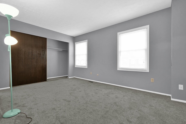 unfurnished bedroom featuring a closet and dark colored carpet