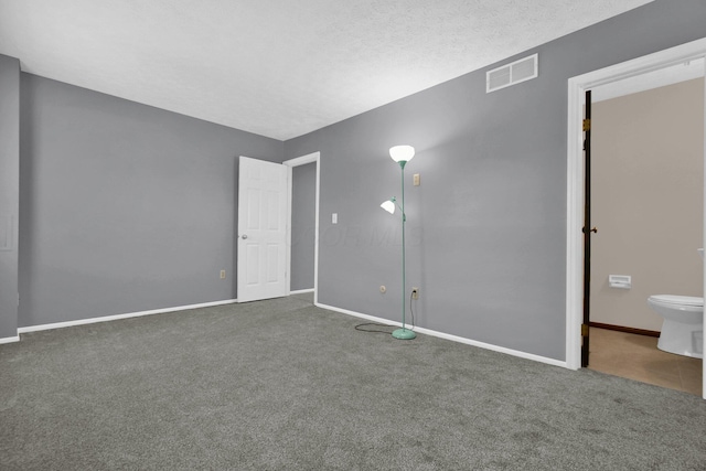 unfurnished bedroom with ensuite bathroom, a textured ceiling, and carpet