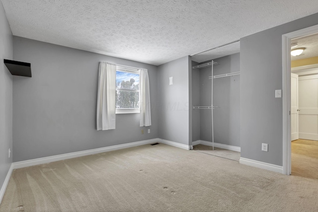 unfurnished bedroom featuring a closet, a textured ceiling, and light colored carpet