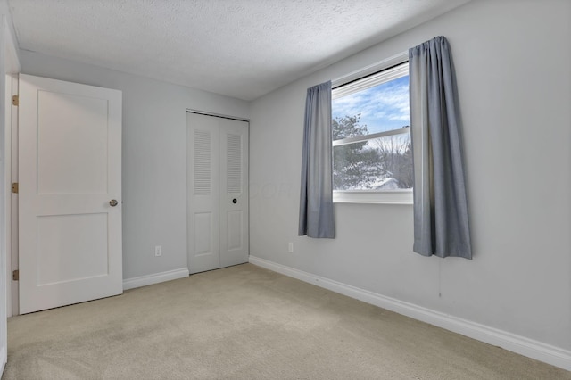 unfurnished bedroom with a textured ceiling, a closet, and light carpet