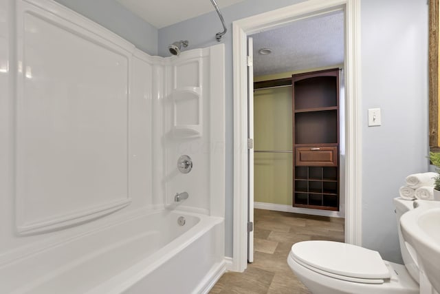 bathroom featuring toilet, a textured ceiling, and shower / bath combination