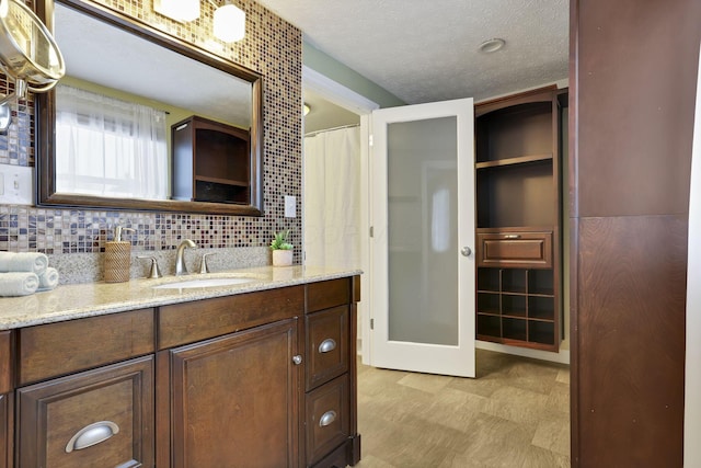 bathroom featuring a textured ceiling, backsplash, and vanity