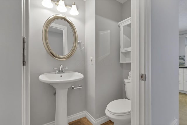 bathroom featuring toilet, sink, and hardwood / wood-style flooring