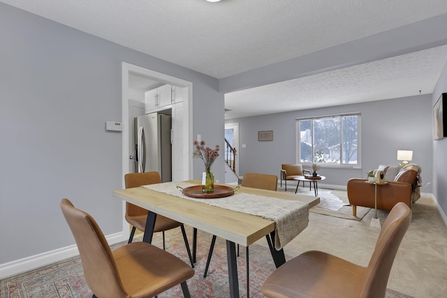 carpeted dining space with a textured ceiling