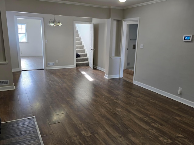 spare room featuring an inviting chandelier, ornamental molding, and dark hardwood / wood-style flooring