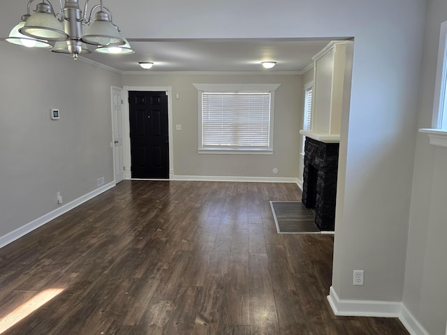 unfurnished living room with ornamental molding, dark hardwood / wood-style floors, and an inviting chandelier