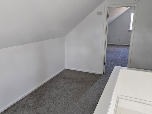 additional living space with dark carpet and vaulted ceiling