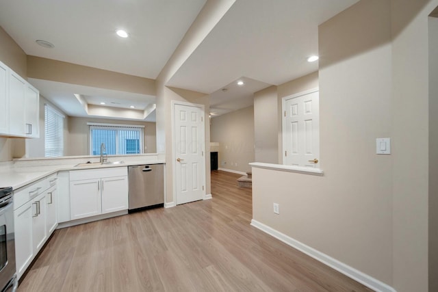 kitchen featuring a raised ceiling, sink, stainless steel dishwasher, light hardwood / wood-style floors, and white cabinetry