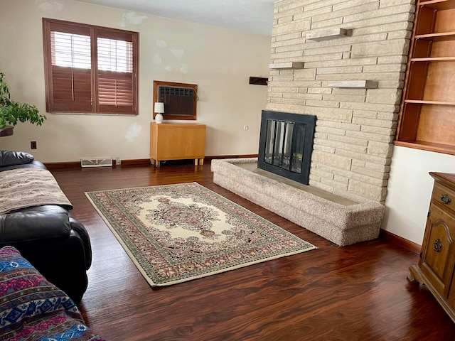 living room with dark hardwood / wood-style floors, a stone fireplace, and a wall mounted AC